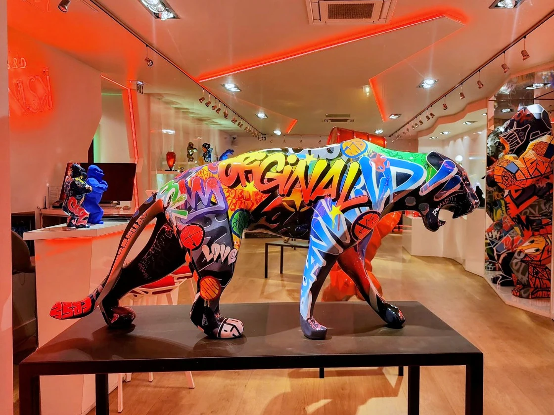 Colourful graffiti-covered panther sculpture displayed on a black table in an art gallery