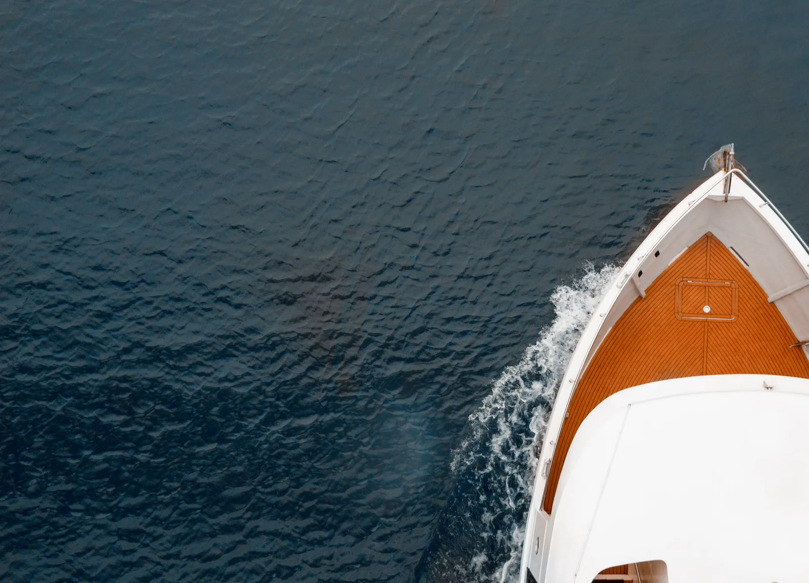 Overhead view of a yacht deck and bow with wake in blue water